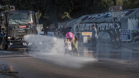 Menschen auf einer Straße stehen im Strahl eines Wasserwerfers, Szene aus einem Protest gegen die Todesstrafe in Jerusalem