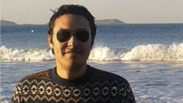 Porträtfoto von Amr Abdelfattah mit dem Meer im Hintergrund. Er trägt eine Sonnenbrille und lächelt in die Kamera.