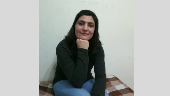 Porträtfoto von Zeynab Jalalian, die ihr Kinn auf ihre rechte geschlossene Hand stützt und ernst in die Kamera blickt.