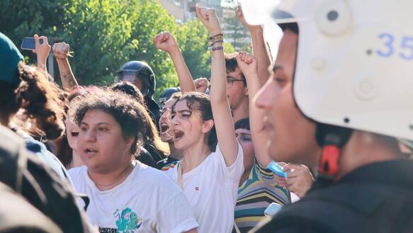 Mehrere Protestierende heben die Faust in die Höhe, ein Polizist steht im Vordergrund