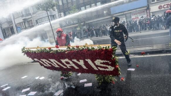 Ein Polizist bei dem Versuch, einem Demonstranten ein mit Blumen bedecktes Banner zu entreißen. Istanbul, 1. Mai 2014