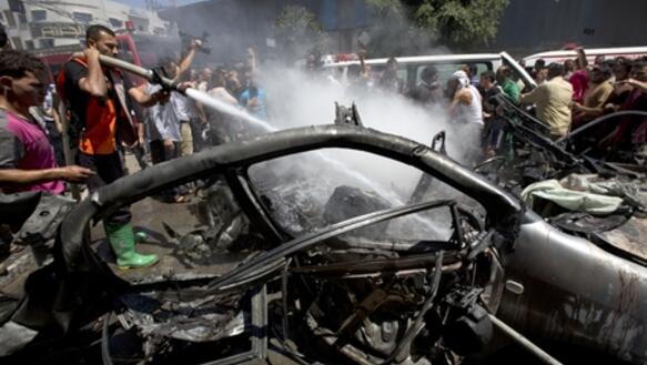 Feuerwehrmänner löschen ein Fahrzeug, das Ziel eines israelischen Luftangriffes geworden war, Gaza Stadt, 8. Juli 2014