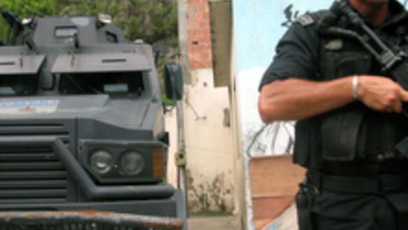 Caveirao/A military police officer stands next to an armoured vehicle, popularly known as the Caveirão, in the Morro Da Fe