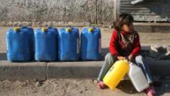Ein palästinensisches Mädchen legt auf dem Weg zum Wasserholen eine Rast ein