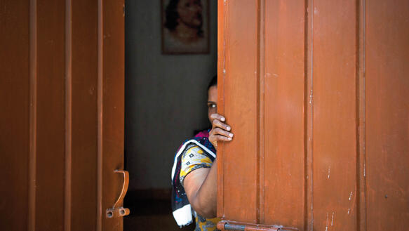 Eine Frau schaut hinter der Tür einer Kirche in Joseph Colony, hervor, Pakistan, 2013