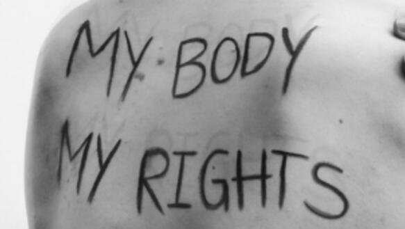 Aufnahme eines Rückens, auf dem geschrieben steht: "My body, my rights". Die fotografierte Person fasst sich mit der linken Hand an die rechte Schulter.