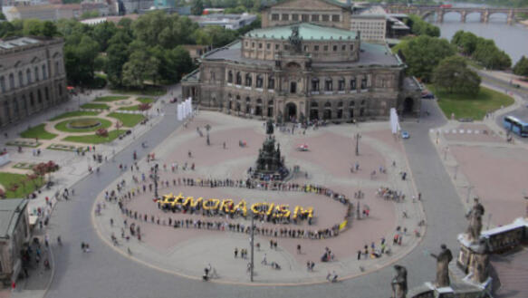 Amnesty-Aktivistinnen und Aktivisten bilden auf dem Theaterplatz in Dresden den Schriftzug #NORACISM