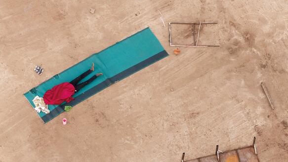 Geflüchteter liegt draußen auf einer Matte in Khartum