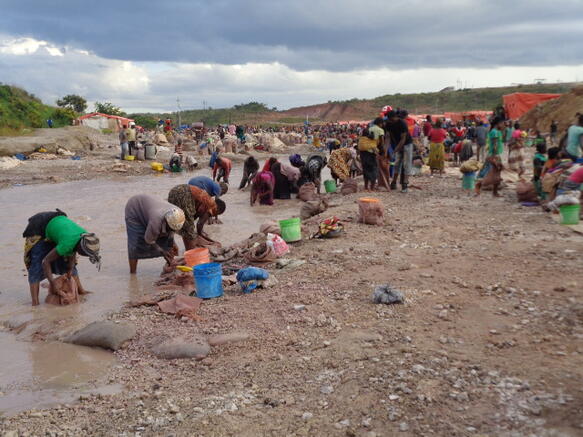 Frauen stehen gebückt in einem Fluss und waschen etwas aus