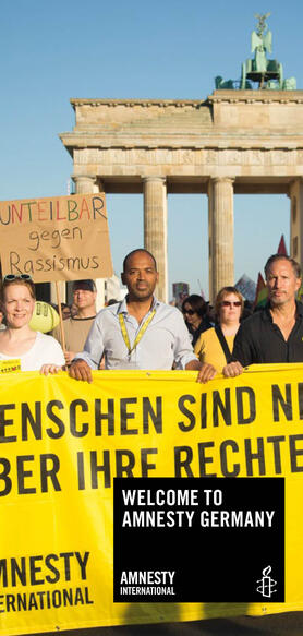 Mehrere Menschen demonstrieren vor dem Brandenburger Tor, sie halten ein Amnesty-Banner in der Hand.