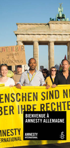 Mehrere Menschen demonstrieren vor dem Brandenburger Tor, sie halten ein Amnesty-Banner in der Hand.