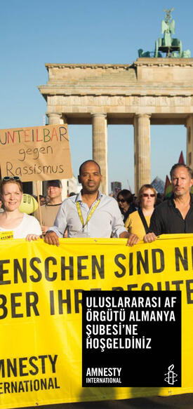 Faltblatt-Cover: Darauf Demonstrierende mit Amnesty-Banner vor dem Brandenburger Tor, darunter Markus N. Beeko (Generalsekretär der deutschen Sektion) sowie der Schauspieler Benno Fürmann