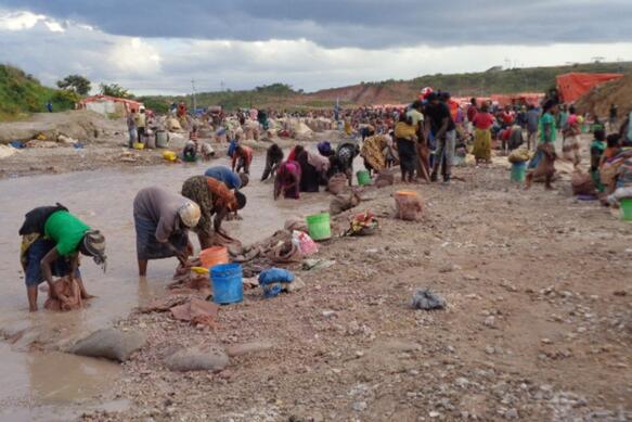 Frauen stehen gebückt in einem Fluss und waschen etwas aus