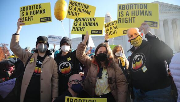 Das Foto zeigt eine circa fünfköpfige Gruppe vor einem Gebäude. Sie halten mit dem Amnesty-Logo bedruckte Schilder hoch, auf denen steht: "Abortion is a human right". 
