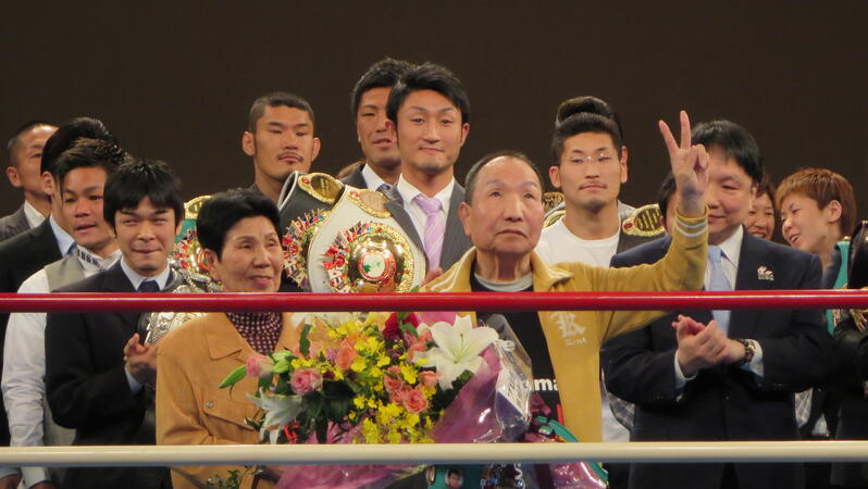 Eine Gruppe von Menschen steht im Boxring, ein Mann und eine Frau halten Blumen in der Hand