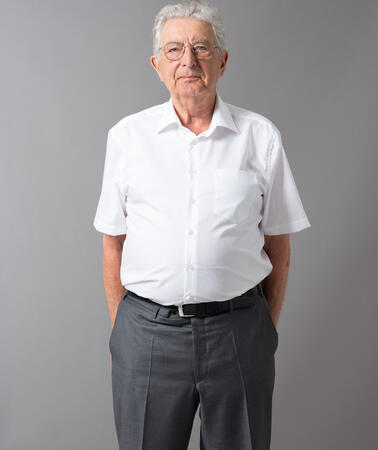 Porträtfoto von einem Mann in weißem Hemd und grauer Hose