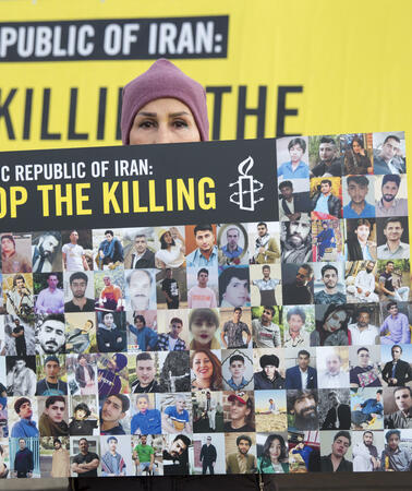 Das Bild zeigt eine Frau, die ein Plakat mit einer Foto-Collage in der Hand hält