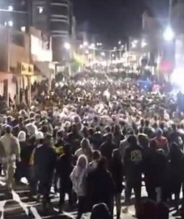 Das Foto zeigt einen großen Demonstrationszug, der nachts durch die beleuchtete Straße in einer Stadt zieht.